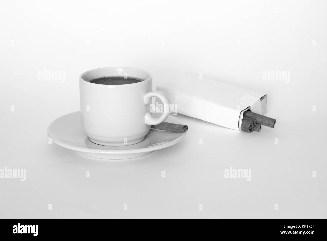 Tazza di caffè e cannella su sfondo bianco. Il concetto di fumo. L'arte della fotografia Foto Stock