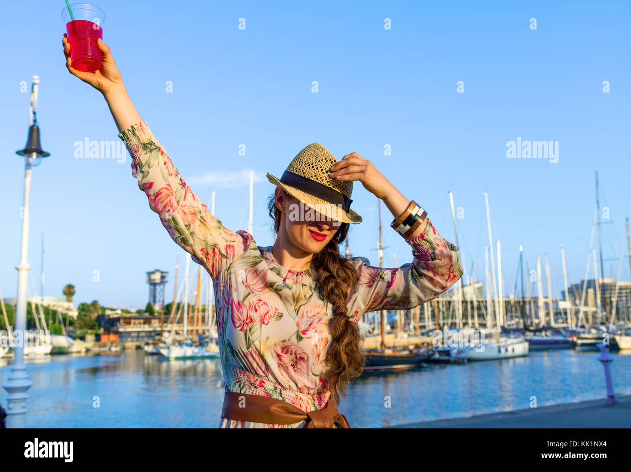 Estate a Barcellona colorati. elegante viaggiatore donna in abiti lunghi e cappello di paglia a Barcellona Spagna con colore rosso brillante bevanda avente tempo di divertimento Foto Stock