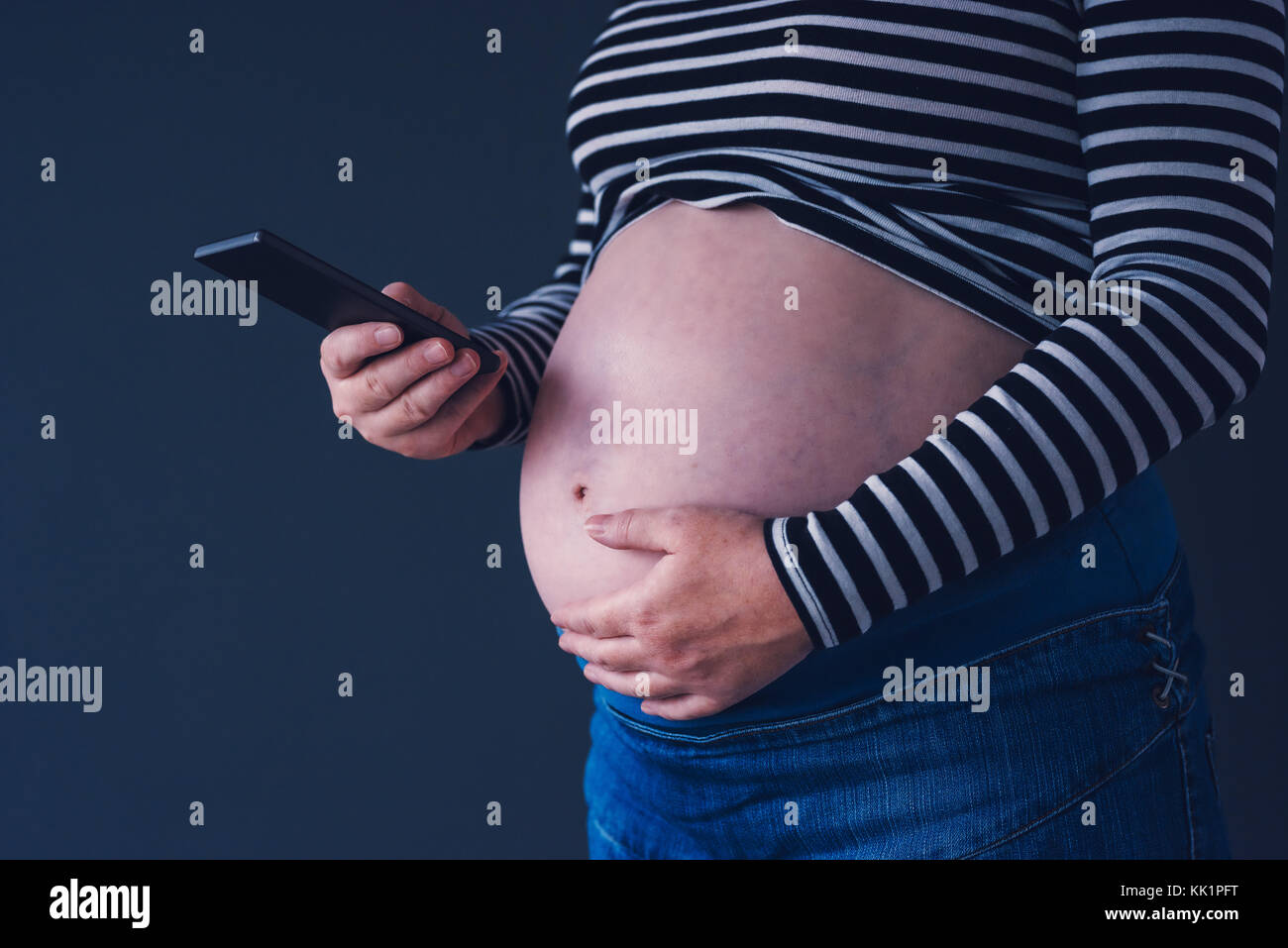 Donna incinta con il suo dispositivo smartphone durante la gravidanza Foto Stock