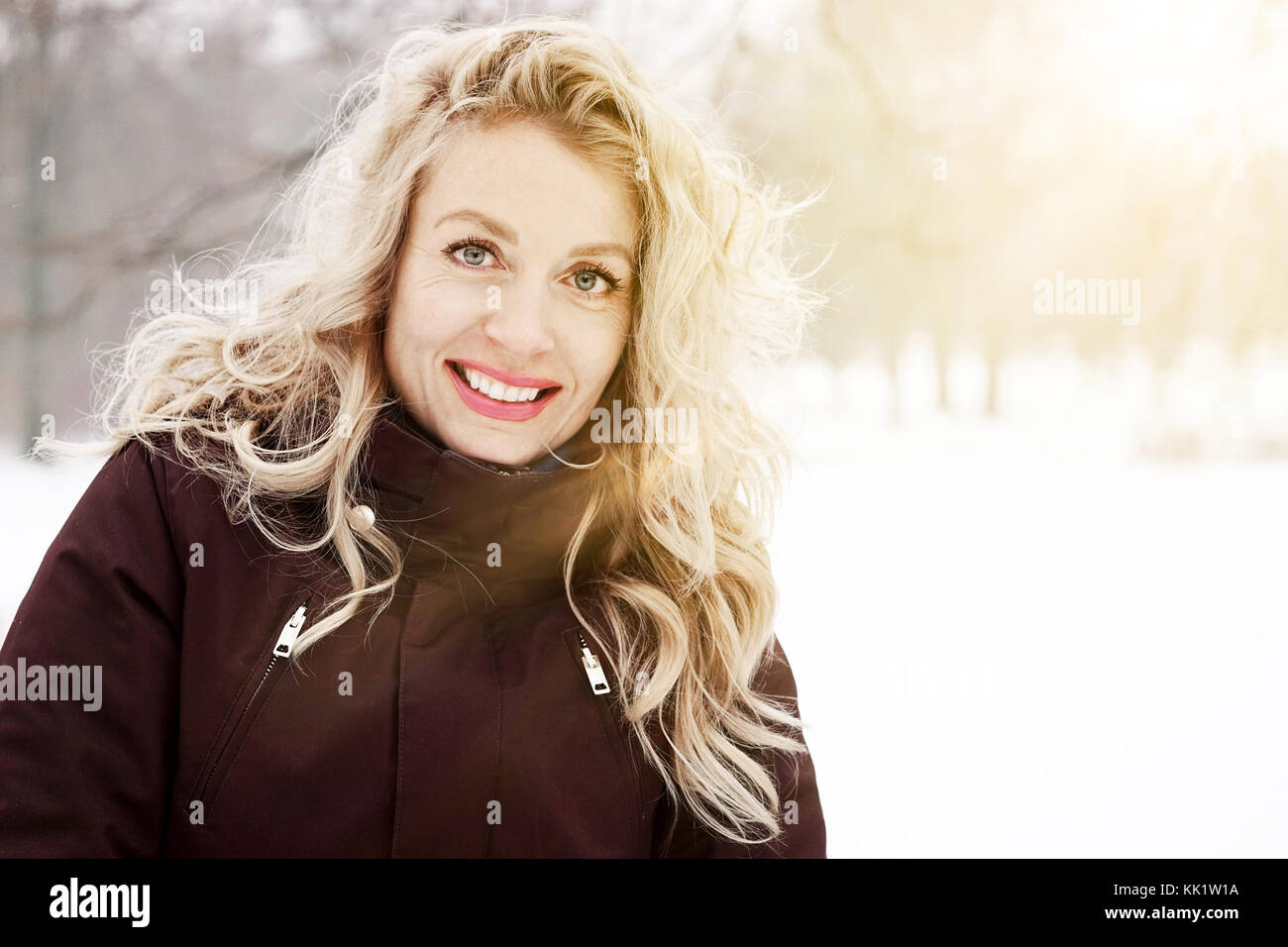 Donna bionda nel paesaggio invernale con sun flare Foto Stock