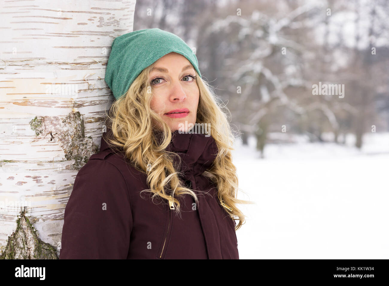 Donna appoggiata ad albero in inverno Foto Stock