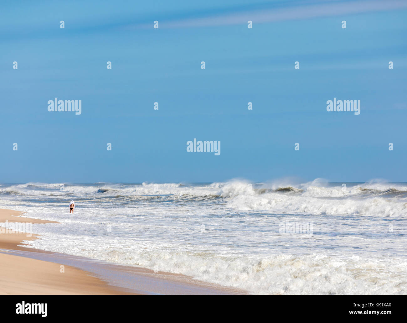 Donna in piedi da solo nel surf di un East Hampton Ocean Beach, est hamptonm, NY Foto Stock