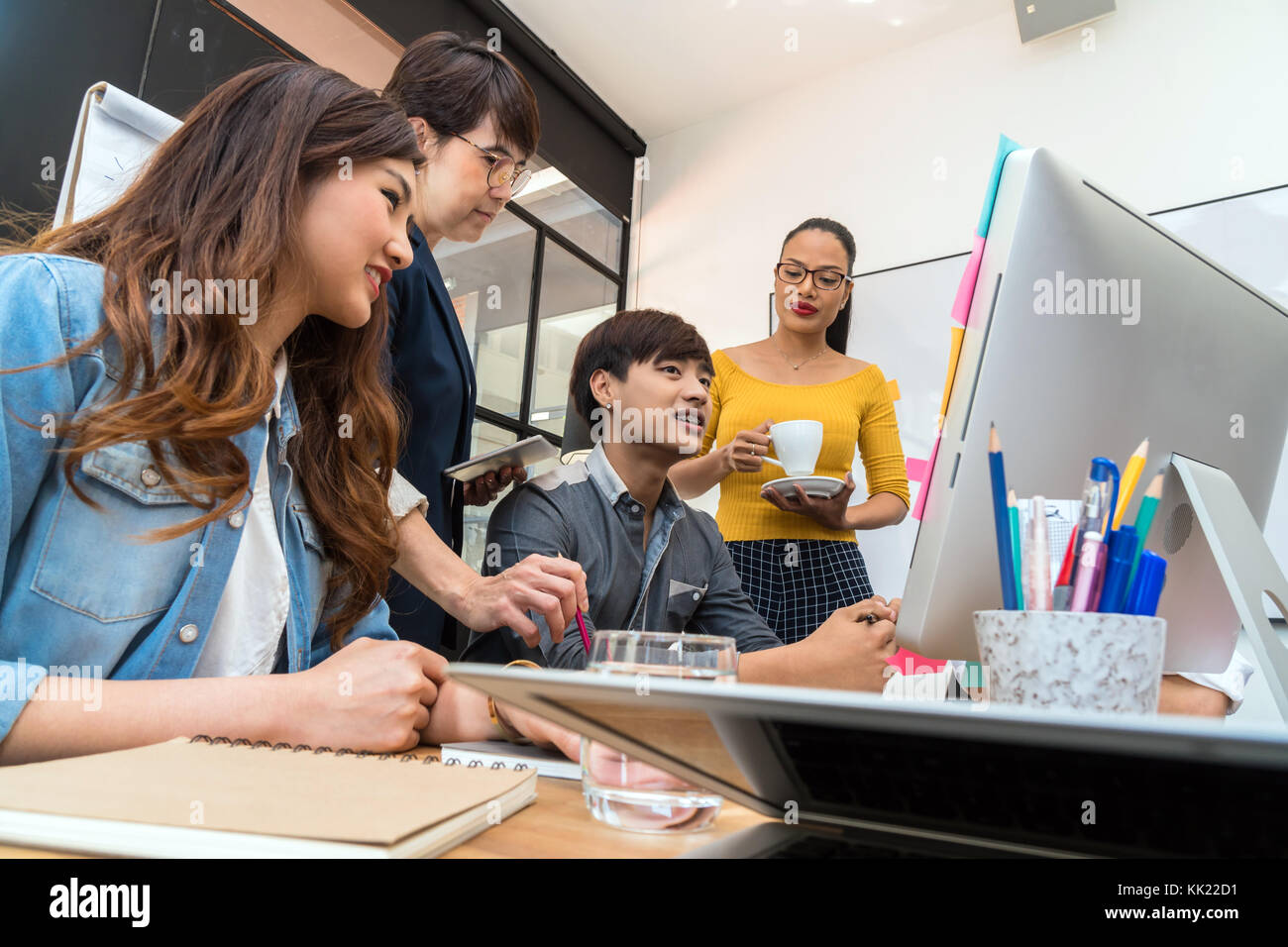 Gruppo di asian multietnica e la gente di affari con abito casual lavorando e di brainstorming insieme con tecnologia computer in ufficio moderno, pers Foto Stock