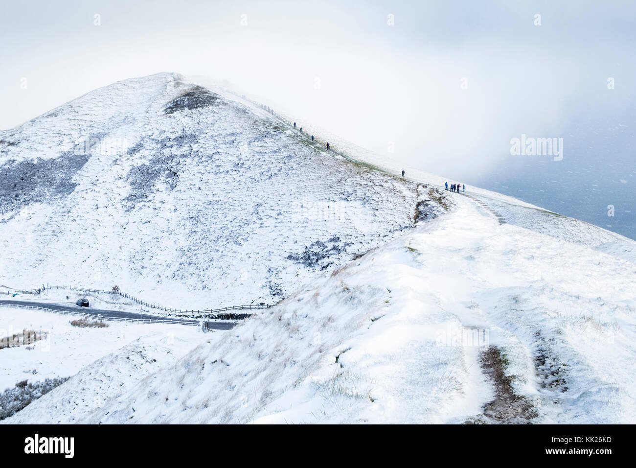 Mam Tor con una copertura di neve e ancora neve caduta. Gli escursionisti sono crescente per la nuvola copriva il tabernacolo il vertice. Derbyshire, Peak District, England, Regno Unito Foto Stock