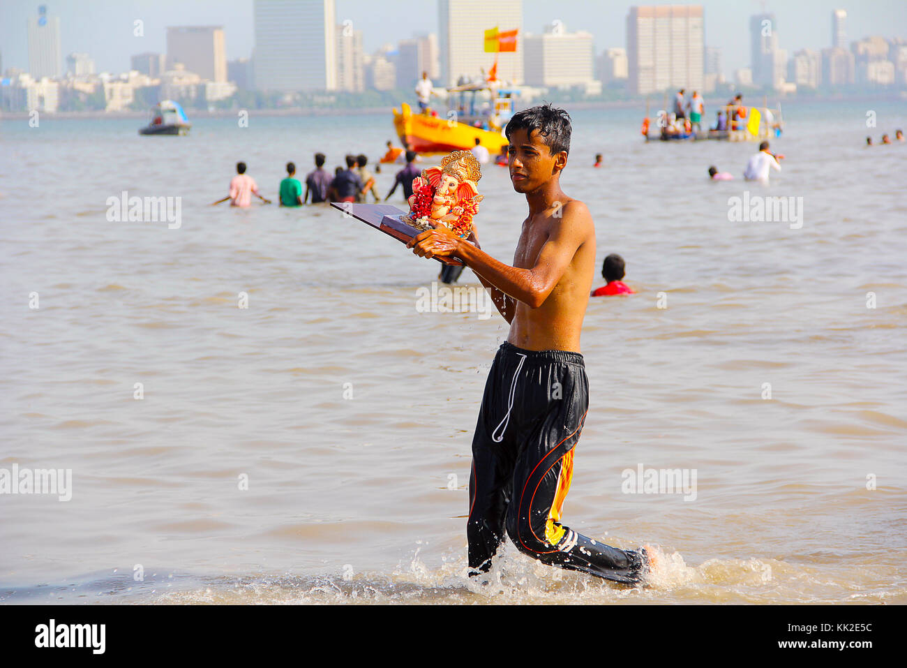 Giovane ragazzo che prende l'idolo Ganapati per l'immersione, Ganapati visarjan, Girgaon Chowpatty, Mumbai Foto Stock