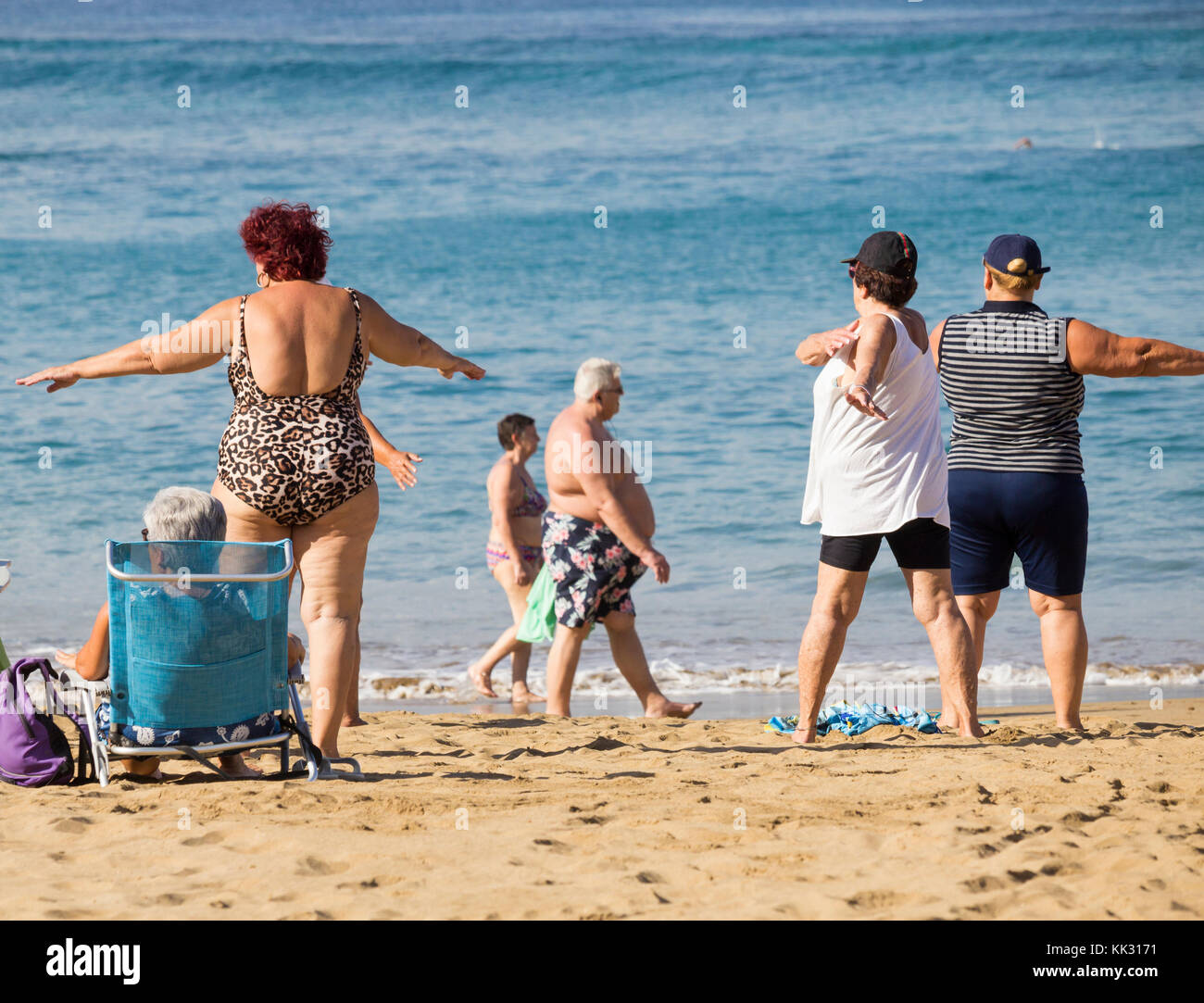 Le donne anziane locali passano attraverso la loro routine alla loro classe quotidiana di mantenersi in forma sulla spiaggia in Spagna. Foto Stock