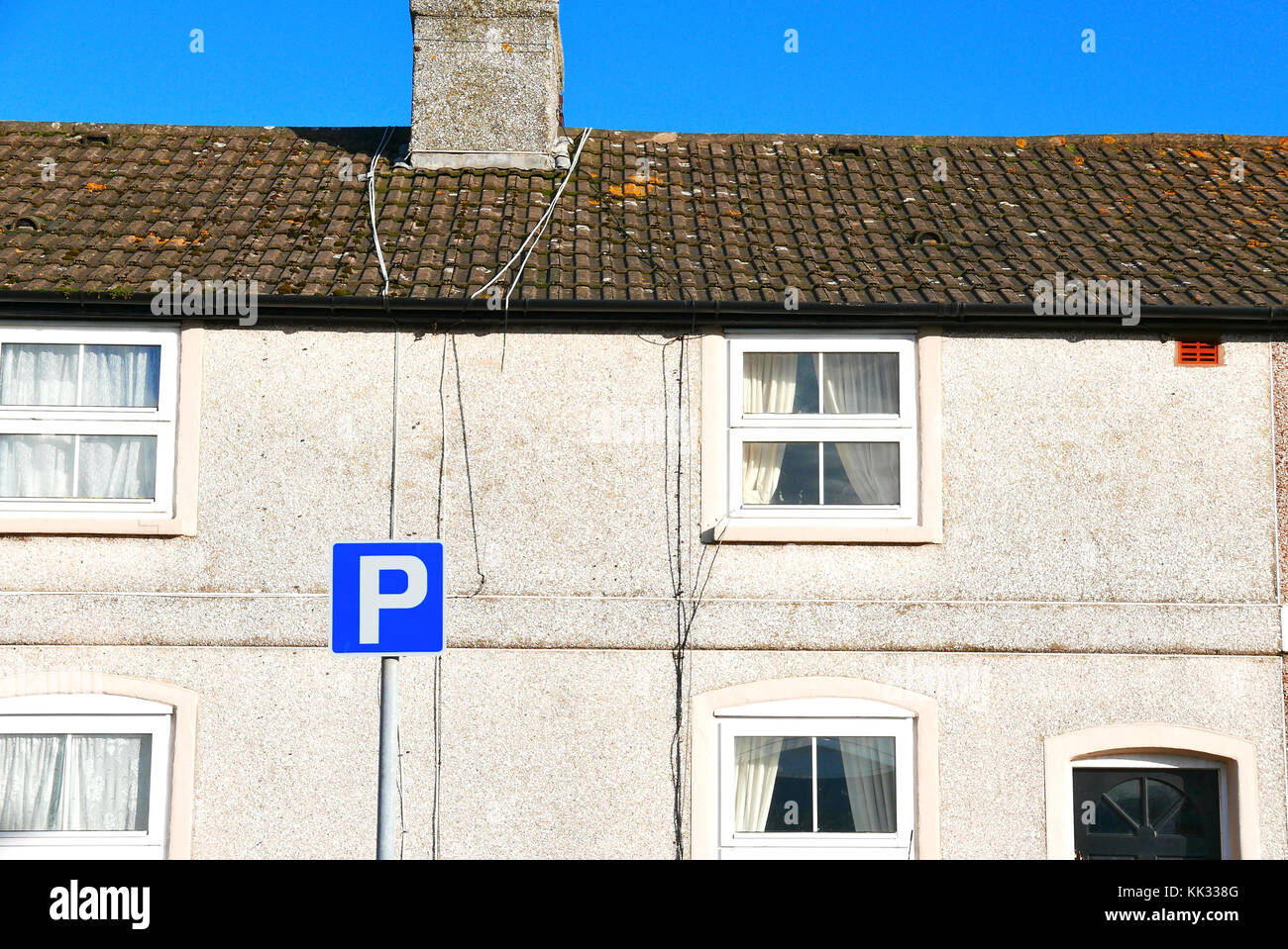 Fila di piccoli cottage con quadrato blu simbolo di parcheggio nella parte anteriore Foto Stock