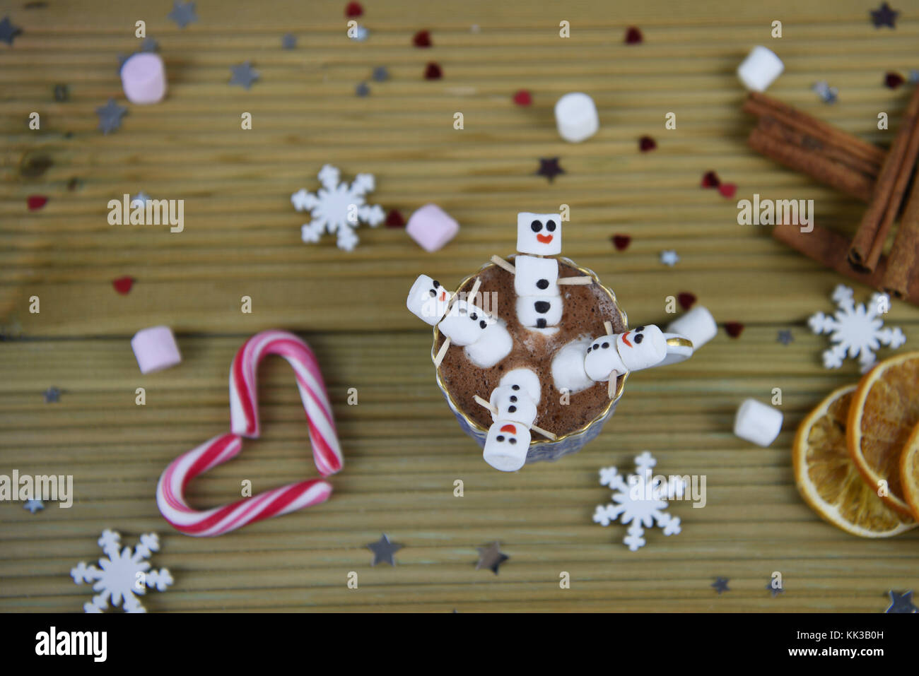 Durante la stagione invernale il cibo e le bevande fotografia immagine con cioccolata calda tazza riempita con felice pupazzo di neve realizzato da marshmallows con cuori rossi in background Foto Stock