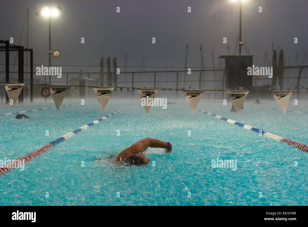 Nuotatore a una piscina scoperta durante piogge pesanti su una sera d'inverno a tel aviv, Israele. Foto Stock