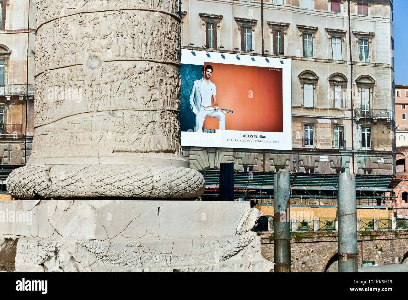 Bacheca pubblicitaria Lacoste su un ponteggio di edifici al Trajan’s Market Forum. Primo piano della colonna di Traiano. Roma, Italia, Europa. Contrasto nuovo e vecchio. Foto Stock
