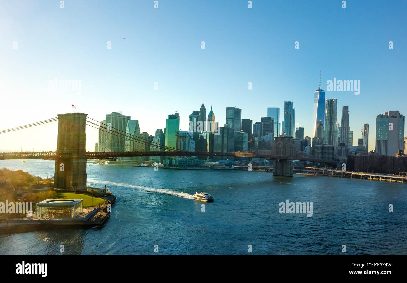 Un East River Ferry passando sotto il ponte di Brooklyn con la parte inferiore della skyline di Manhattan in background Foto Stock