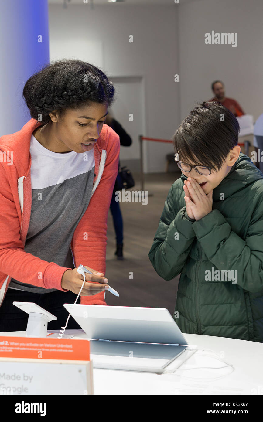 Un addetto allo stand mostra un entusiasta Asian American boy nuova tecnologia dei computer all'interno del Google pop up store sulla Fifth Avenue a Manhattan, New York City Foto Stock