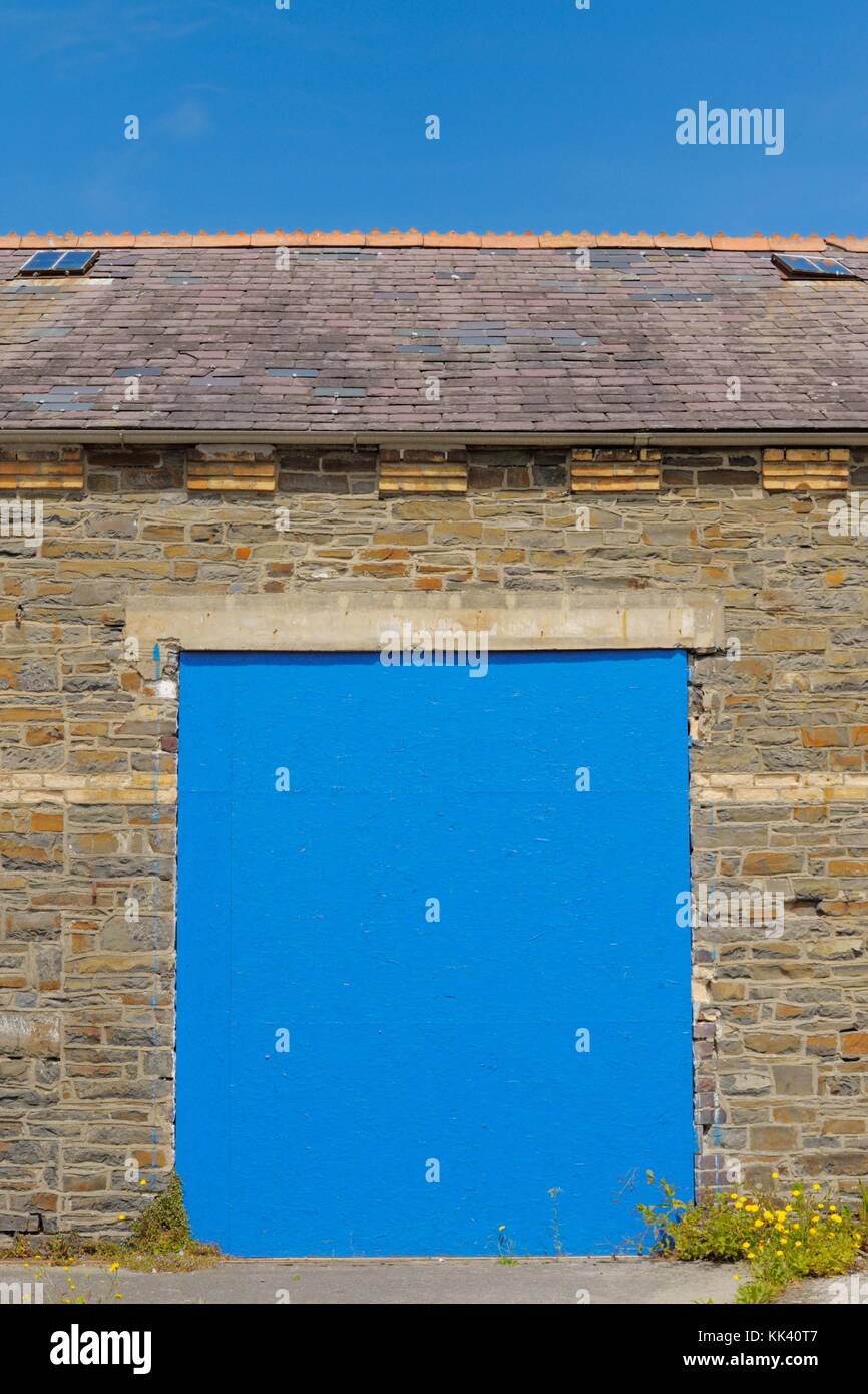 Pianura porta blu impostare ina muro di pietra withblue cielo sopra, Wales, Regno Unito Foto Stock