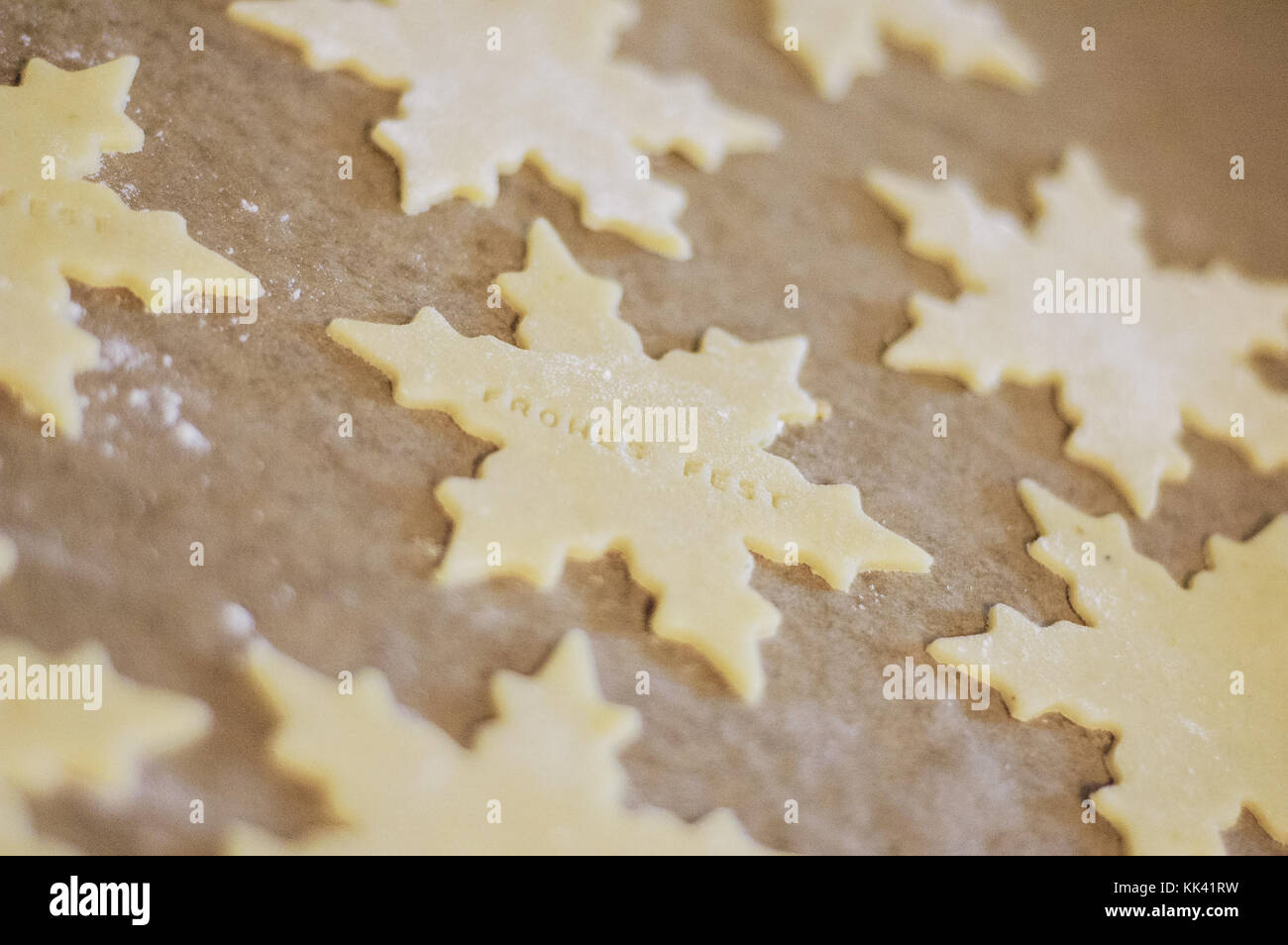 Biscotti di Natale sottilmente laminati e tagliati in forma di stella dicendo le parole tedesche frohes fest, che significa vacanze felici, su carta pergamena sul bakin Foto Stock