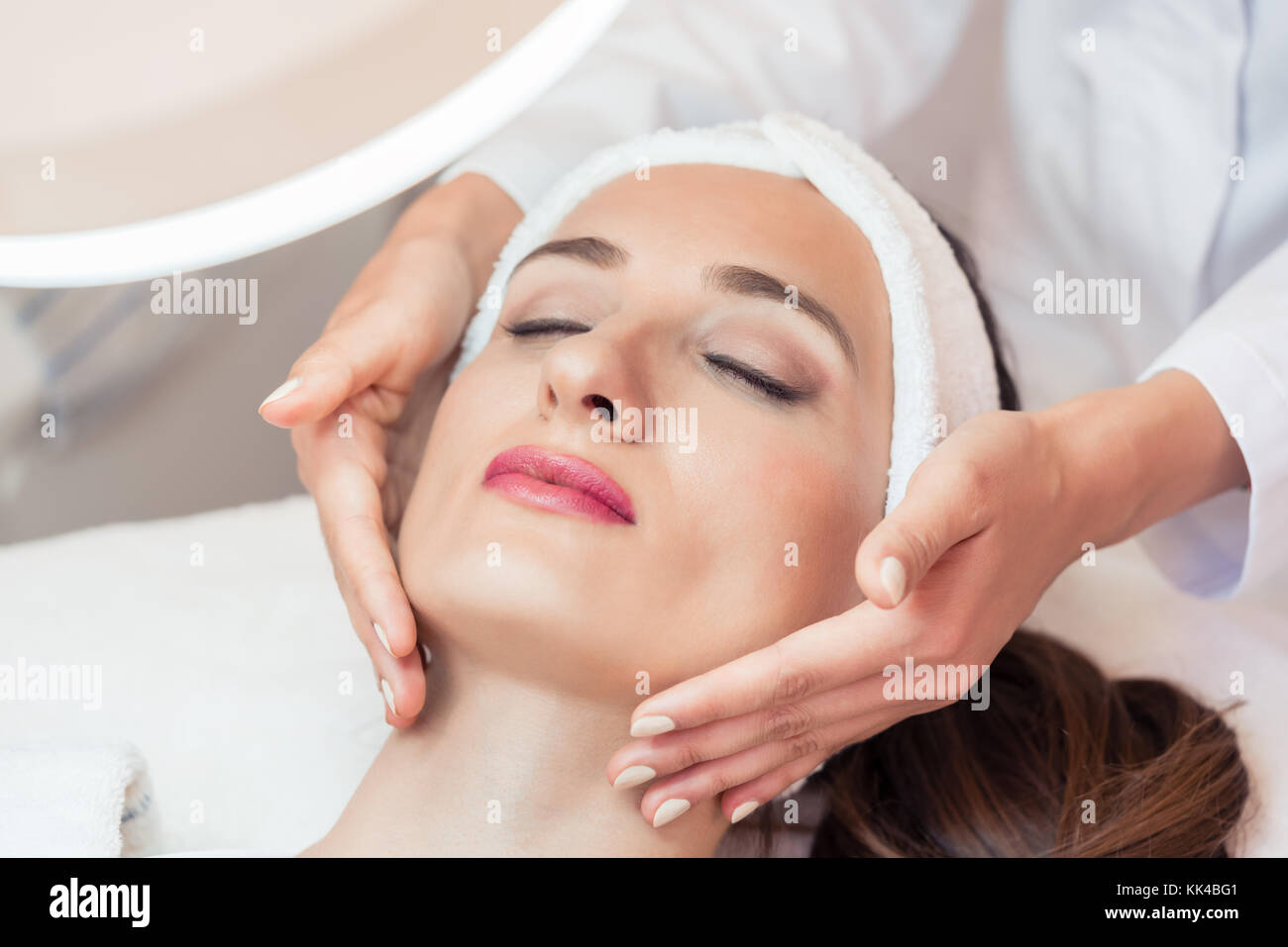 Bella donna rilassante durante il massaggio del viso per il ringiovanimento Foto Stock