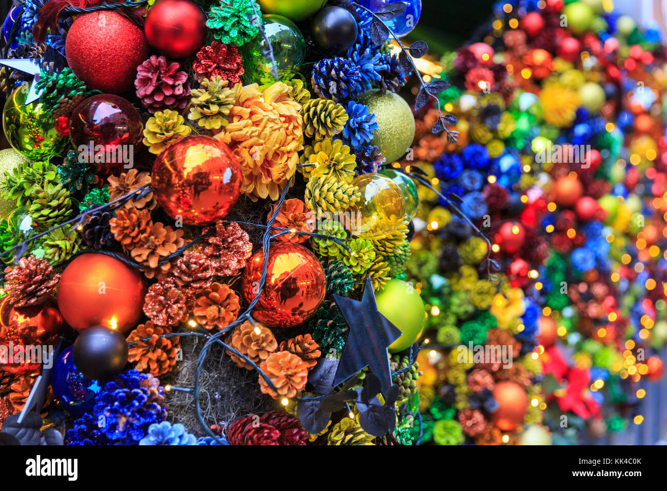 Baubles festosa, luminose colorate decorazioni di Natale, coni e baubles a Londra, Regno Unito Foto Stock