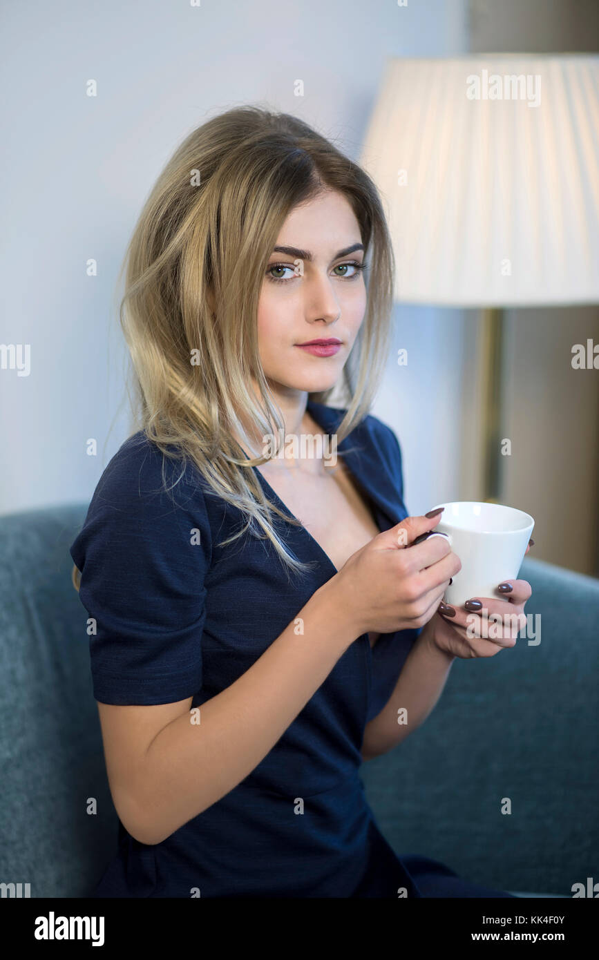 Giovane donna di affari a bere caffè e guardando la telecamera. Foto Stock