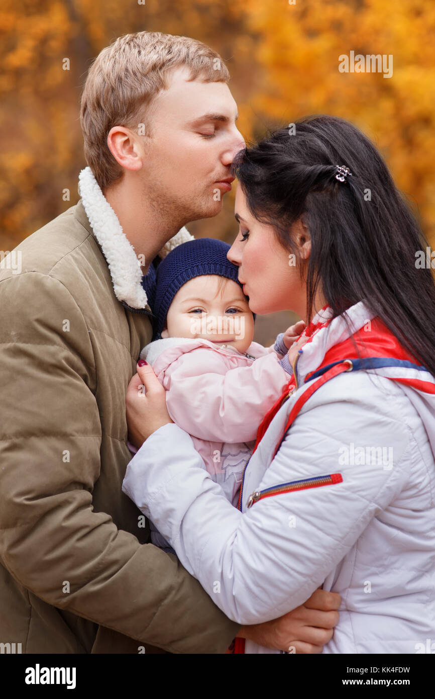 I giovani genitori con la piccola figlia in autunno foresta. mamma e papà holding Baby girl in mani. famiglia felice, amore parentale stagione autunnale concept Foto Stock