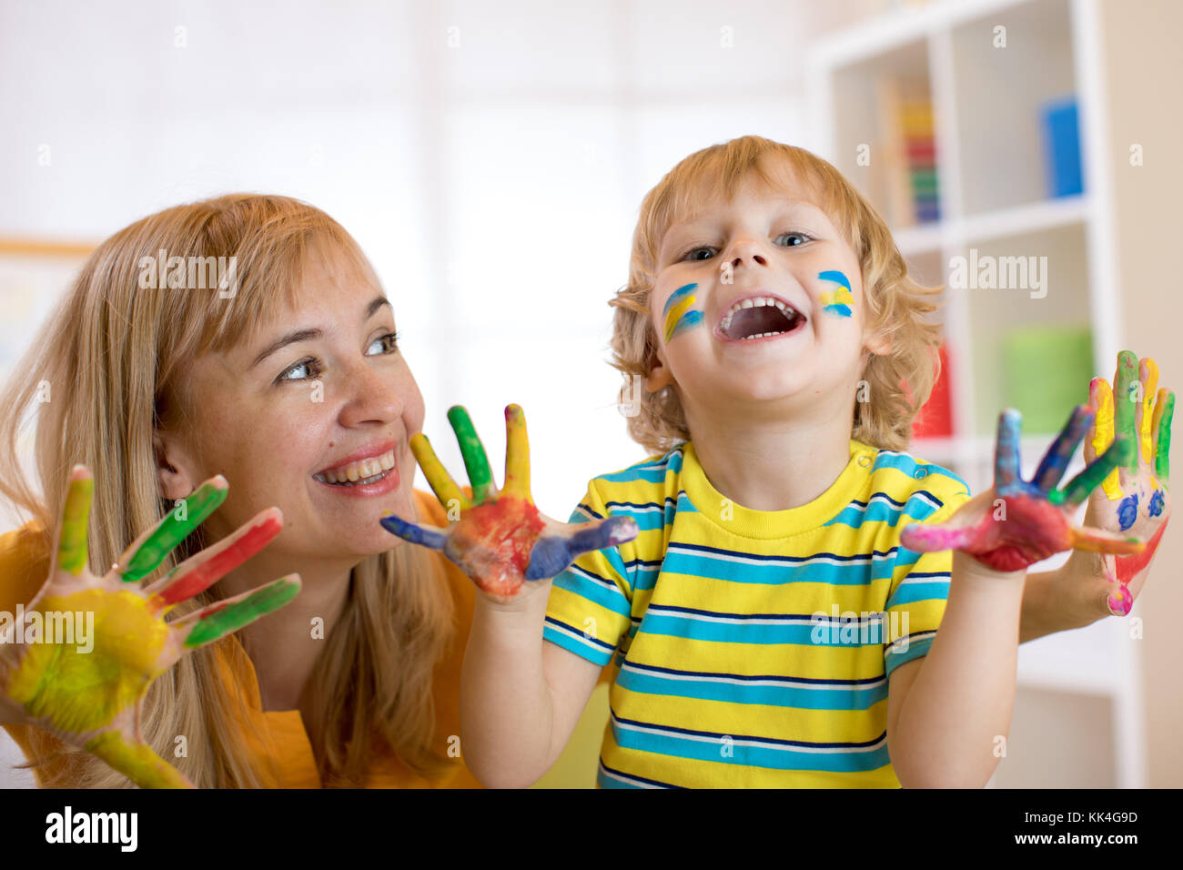 Sorridente ragazzo bambino e sua madre divertendosi e mostrando le mani dipinte di vernici colorate Foto Stock