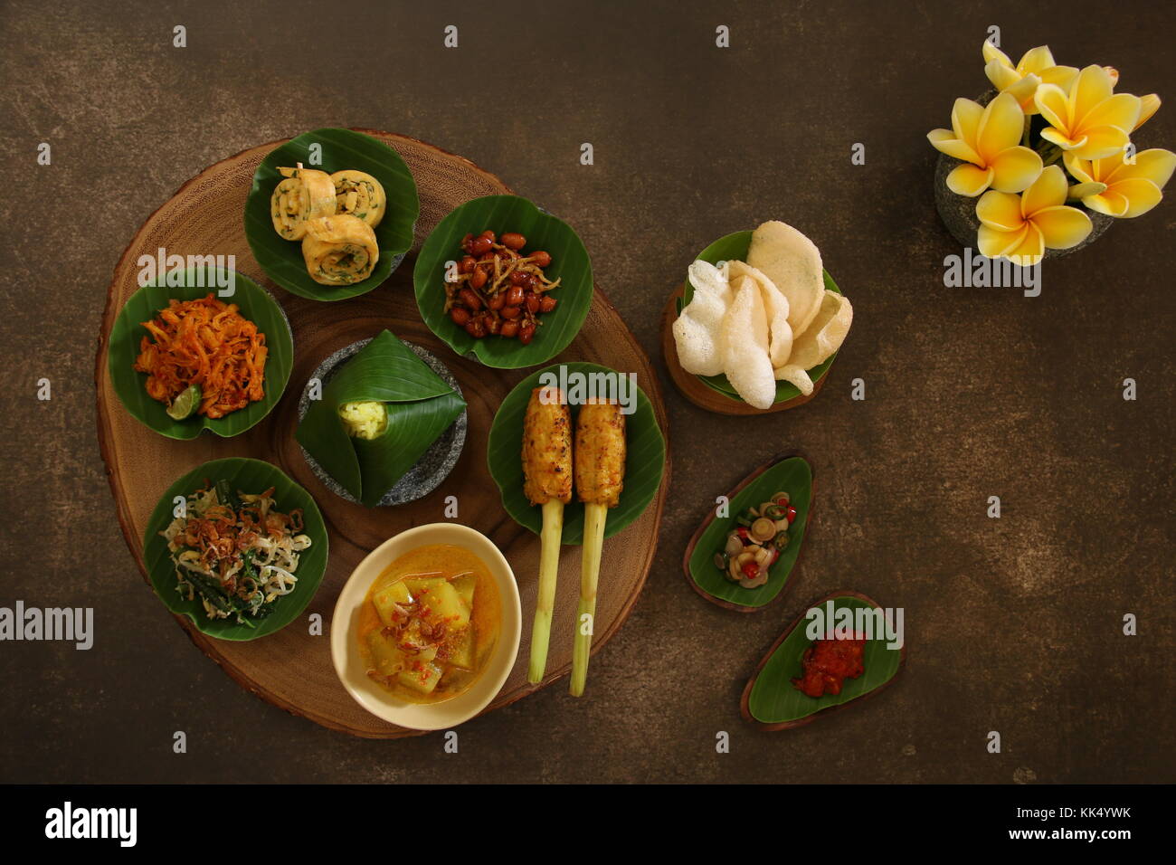 Cibo balinese sampler. balinese assortiti piatti serviti in piccole porzioni su mini mortaio di pietra poi disposti sulla tavola di legno. Foto Stock