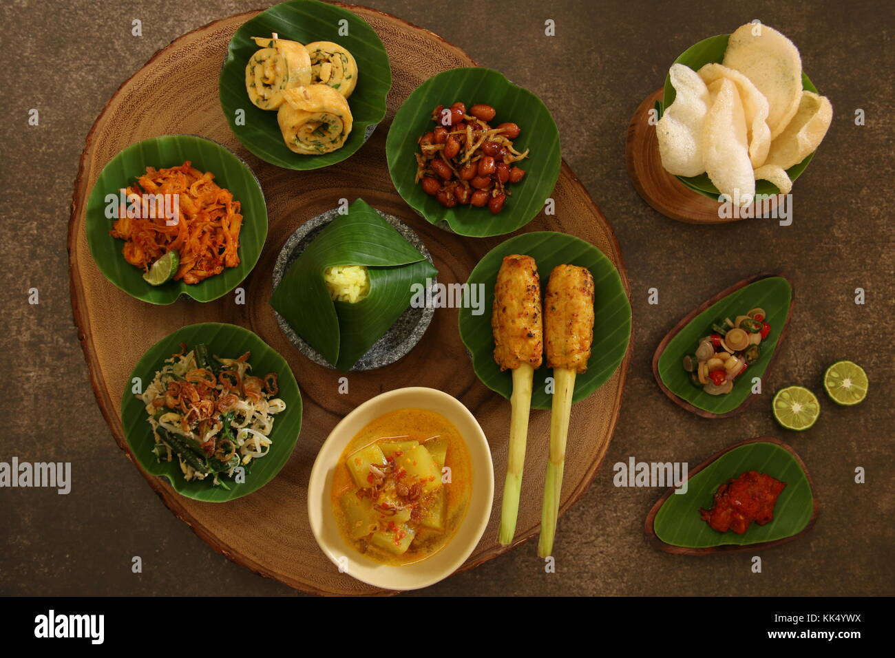 Cibo Balinese campionatore. Un assortimento di piatti in stile Balinese servito in piccole porzioni su mini mortaio di pietra poi disposti sulla tavola di legno. Foto Stock