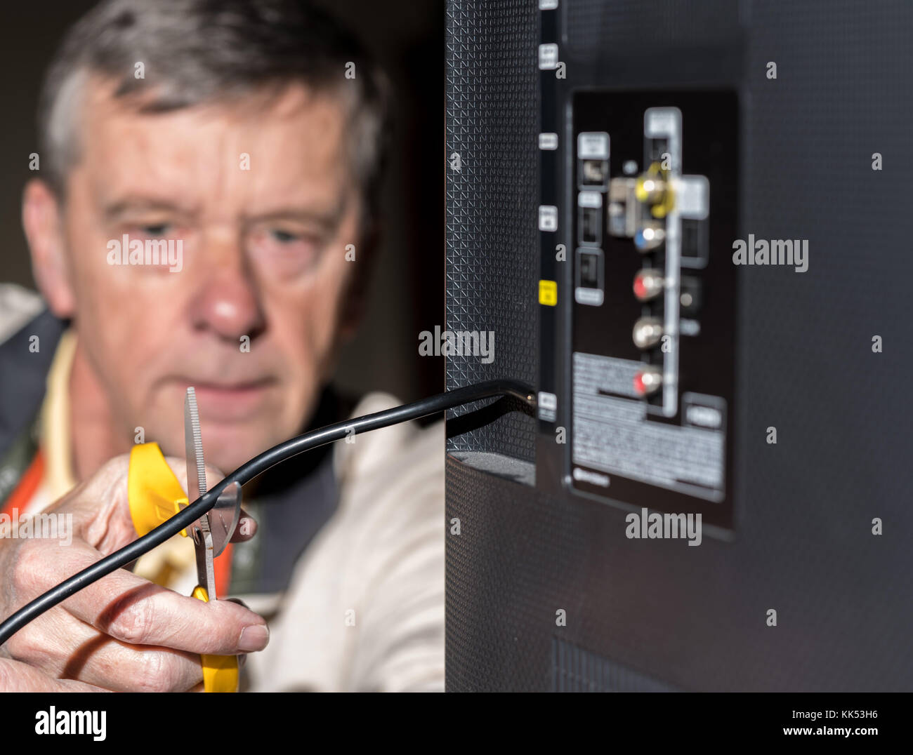 Uomo senior di tagliare il cavo di alimentazione sul cavo del suo pacchetto TV Foto Stock