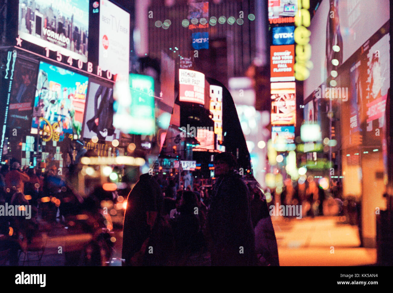 Doppia esposizione della donna che cammina attraverso colorate e luminose times square di new york city Foto Stock