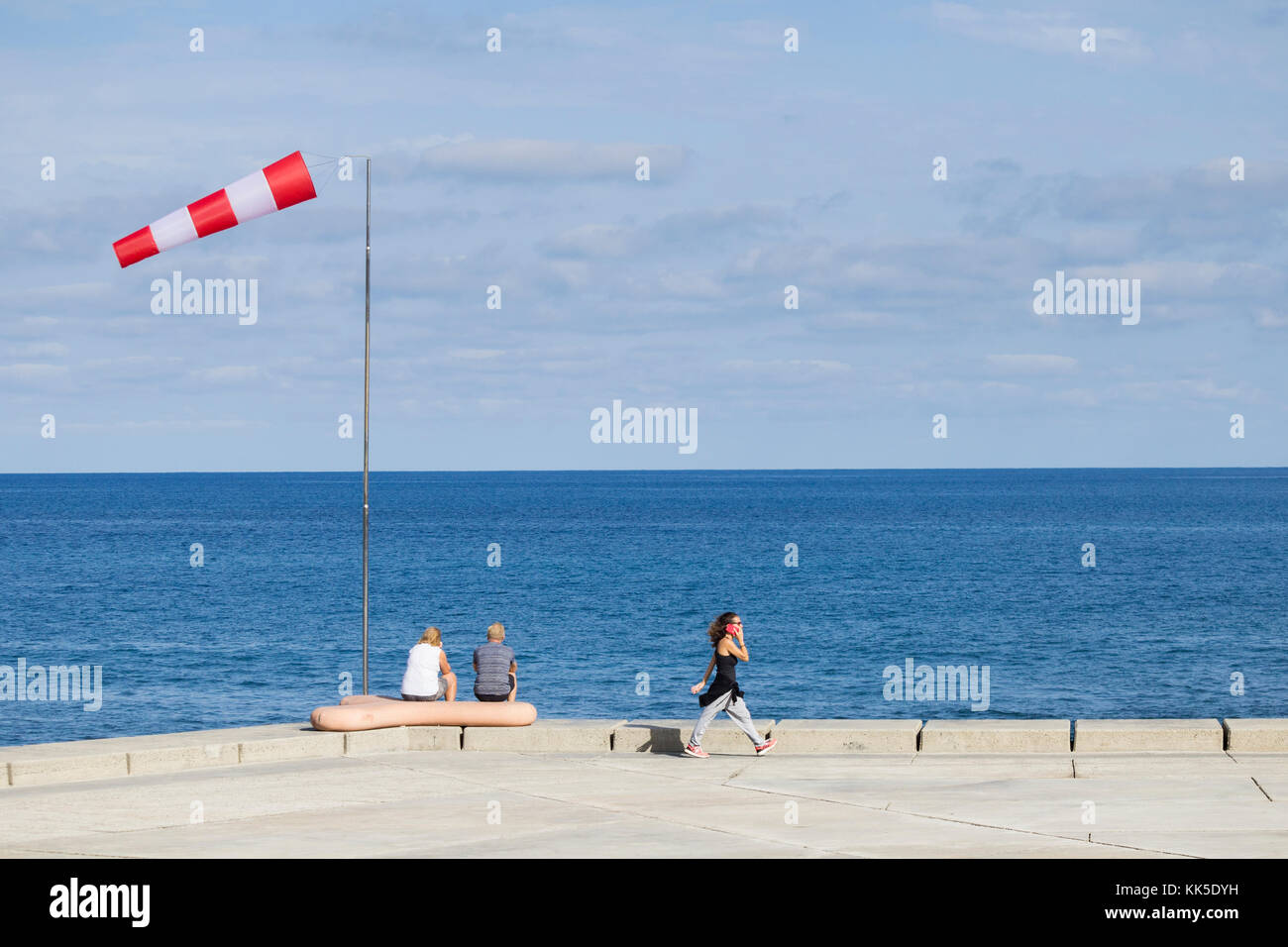 Vista posteriore di una coppia matura seduta sotto la calza a vento che guarda al mare Foto Stock