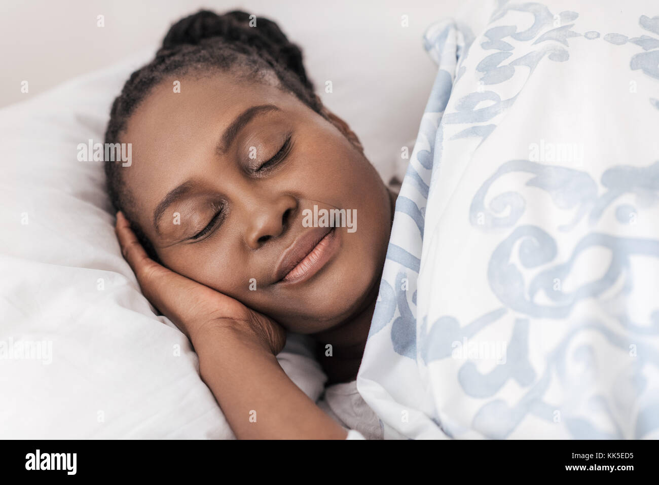 Giovane donna africana dormire nel suo letto a casa Foto Stock