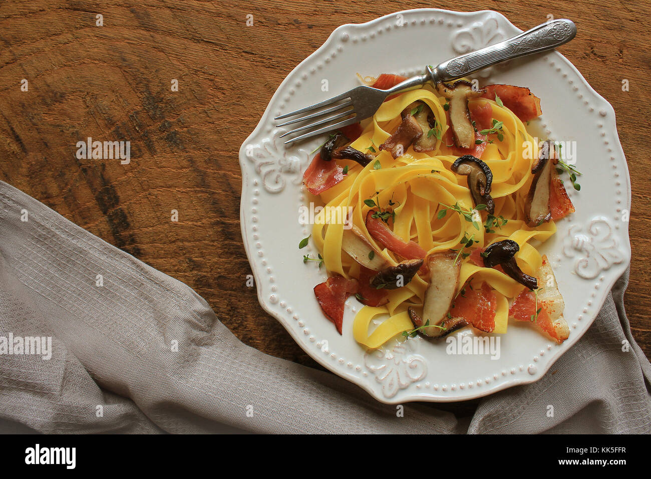 Tagliatelle con funghi commestibili e bacon in legno rustico bacground . Vista superiore . Foto Stock