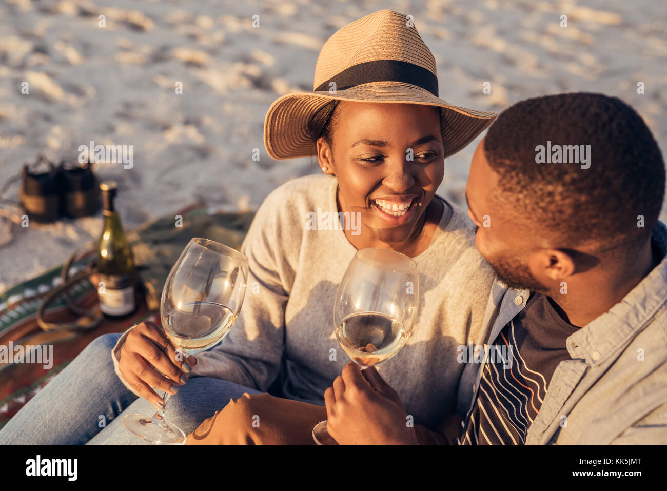Felice giovane africano giovane bevendo vino insieme in spiaggia Foto Stock
