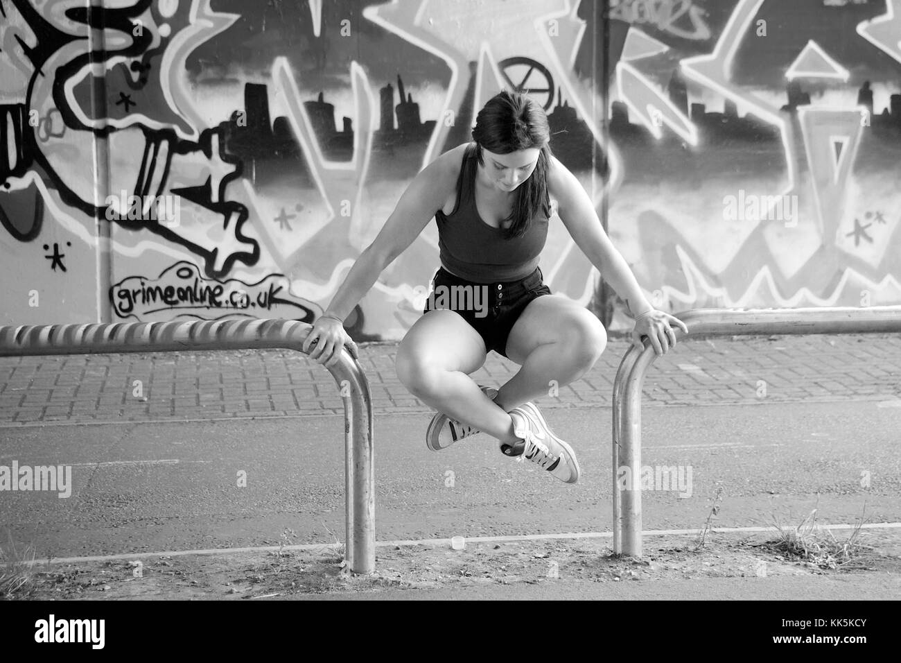 Ragazza facendo esercizi in posizione anoutdoor con un background di graffiti Foto Stock