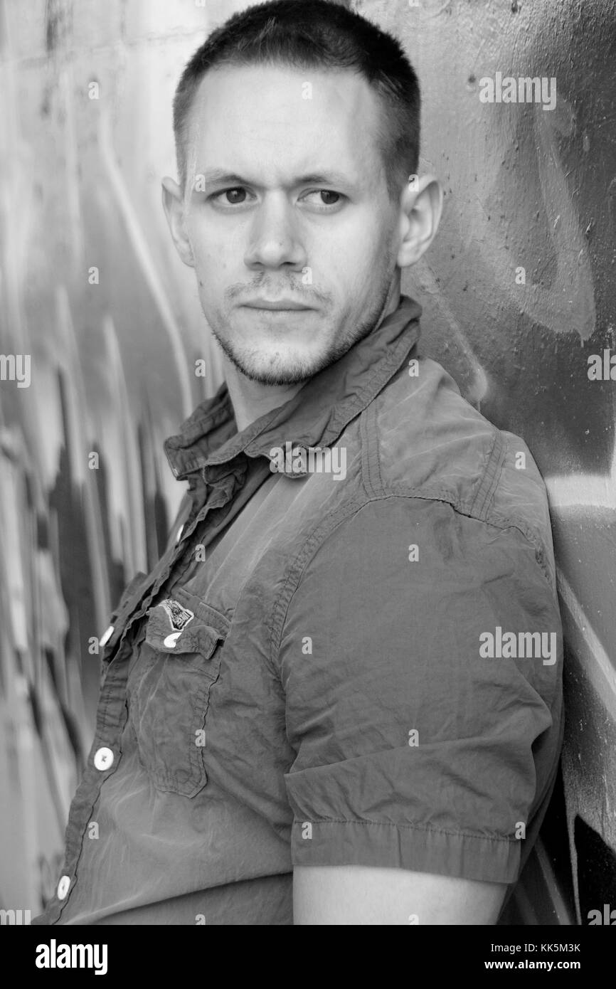 Muscolare di giovane uomo in jeans e una maglietta blu contro uno sfondo di graffiti Foto Stock