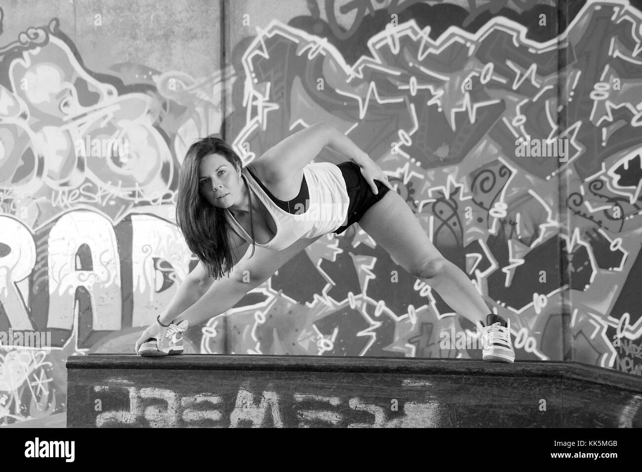 Ragazza facendo esercizi in posizione anoutdoor con un background di graffiti Foto Stock