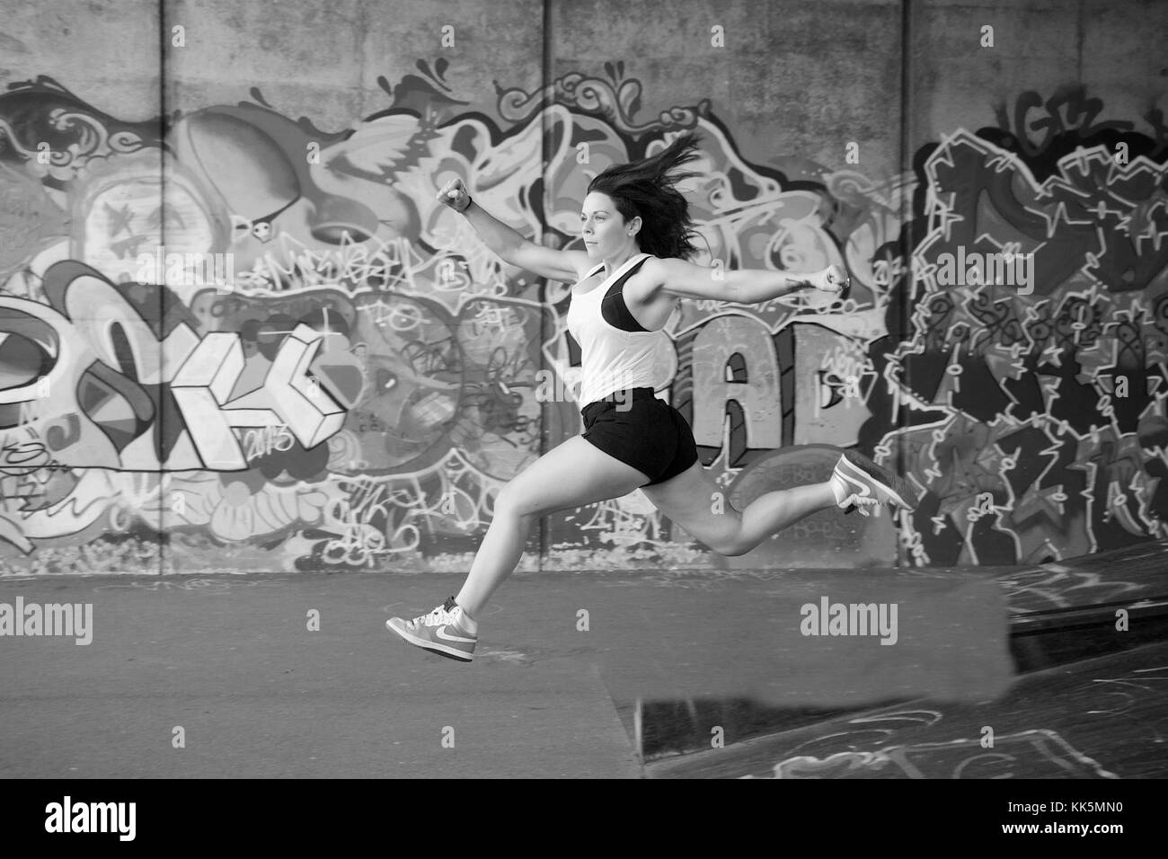 Ragazza facendo esercizi in posizione anoutdoor con un background di graffiti Foto Stock