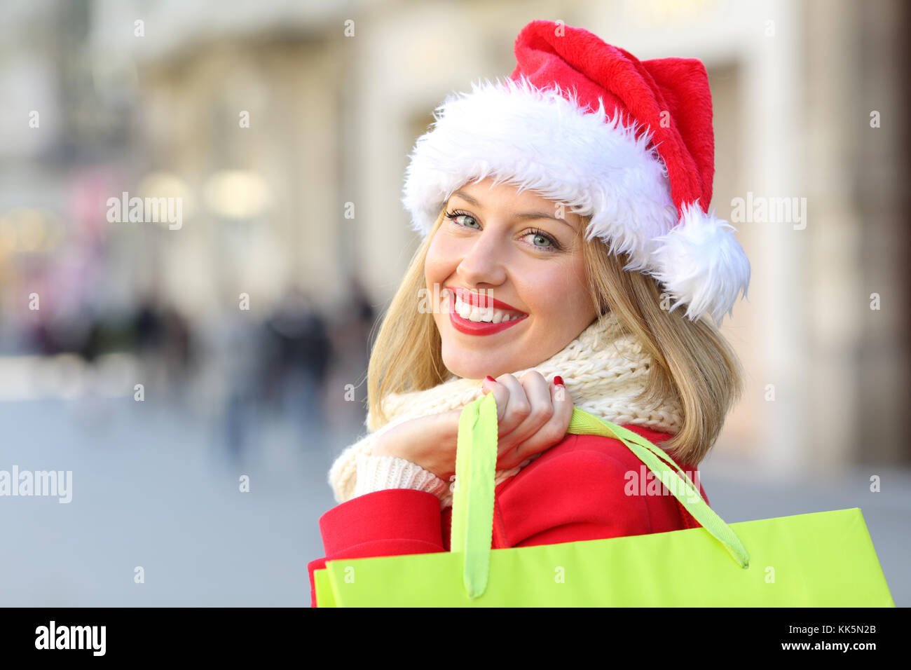 Ritratto di una ragazza felice indossando santa claus hat shopping a Natale ti guarda all'aperto sulla strada Foto Stock