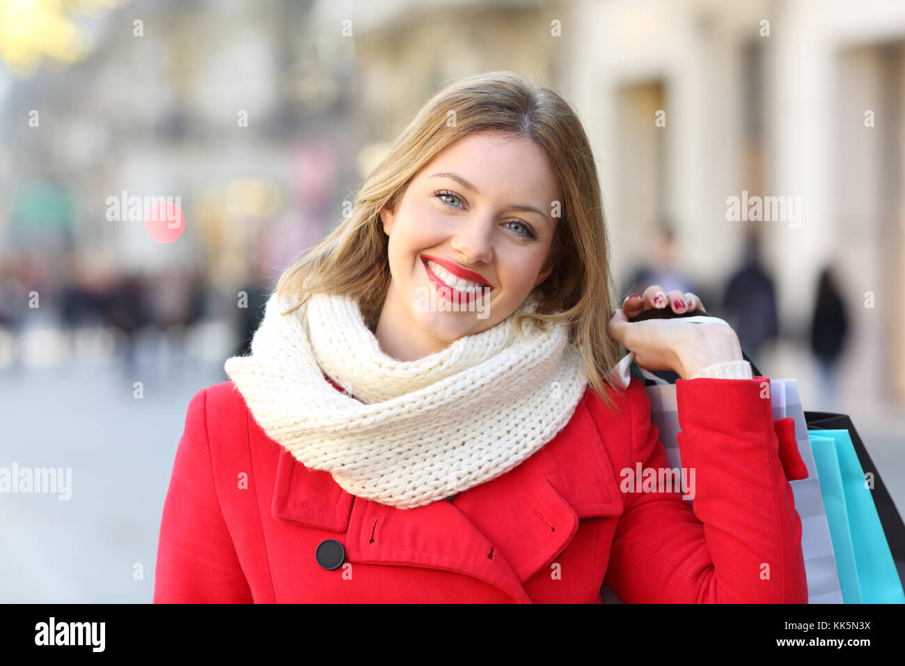 Vista anteriore verticale di un felice shopper guardando la fotocamera in inverno sulla strada Foto Stock