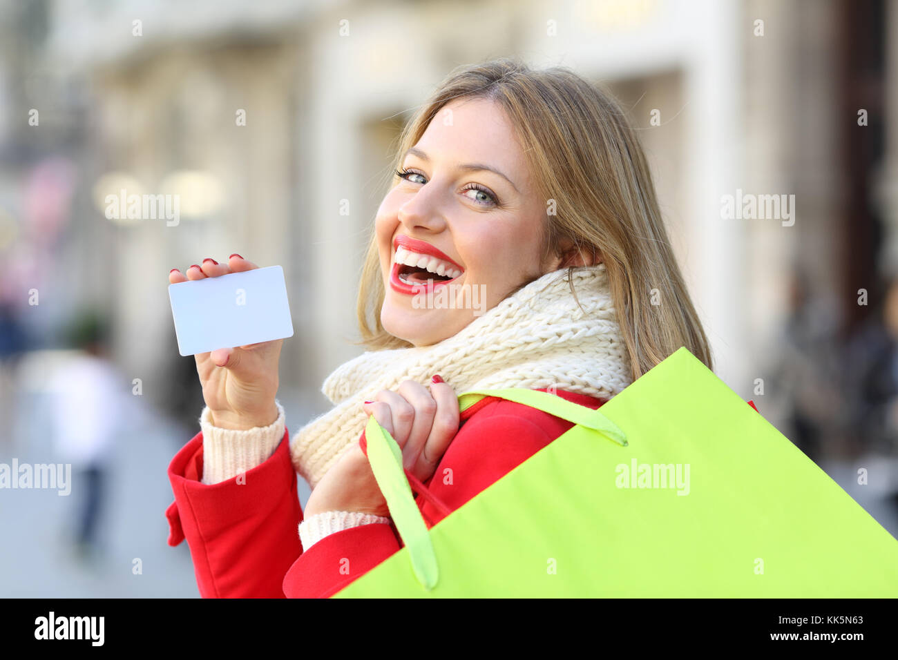 Shopper che mostra un fustellato carta di credito e tenendo le borse della spesa in inverno all'aperto sulla strada Foto Stock