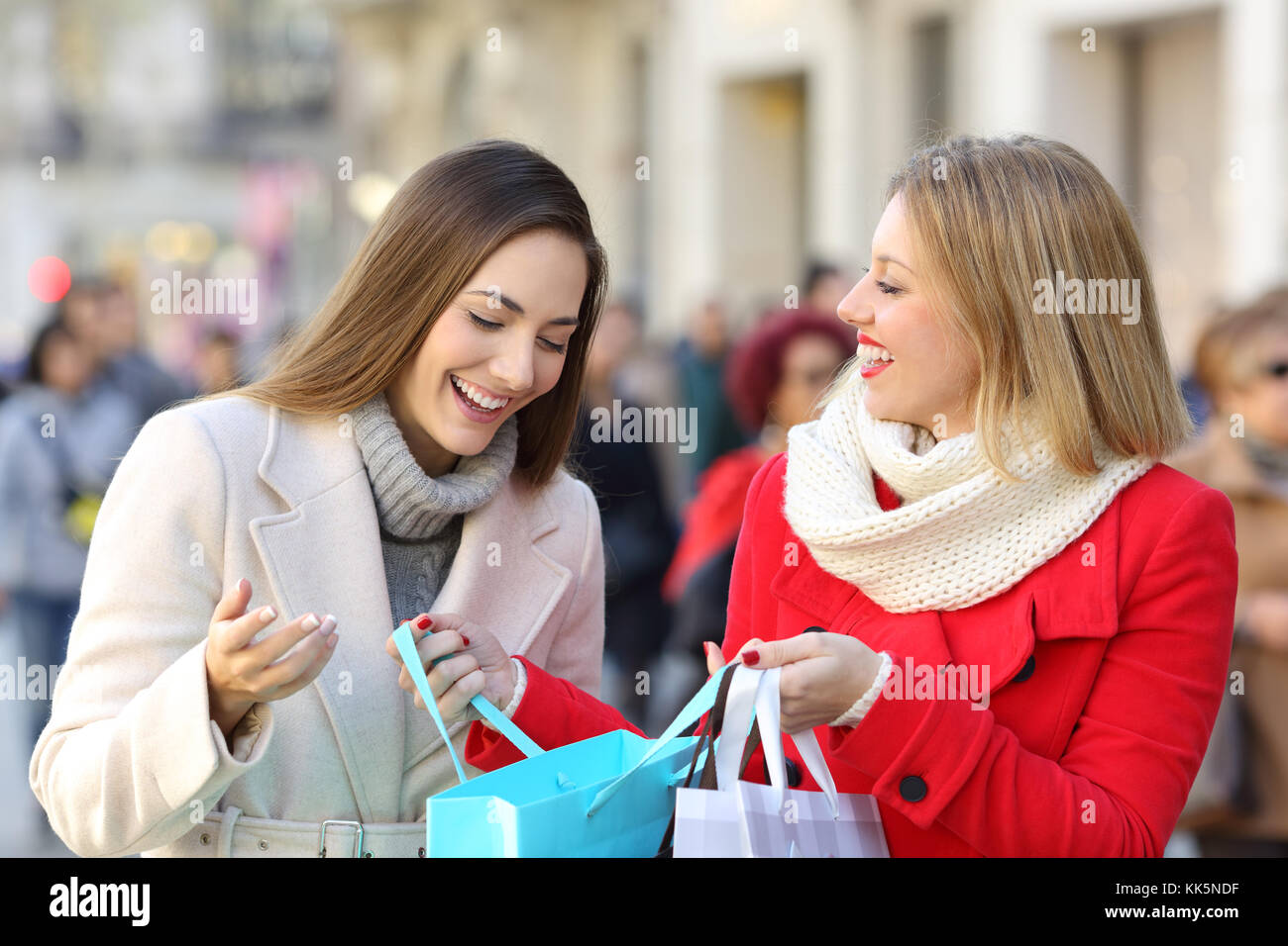 Due acquirenti fatto shopping e che presentano i prodotti all'esterno su strada in inverno Foto Stock