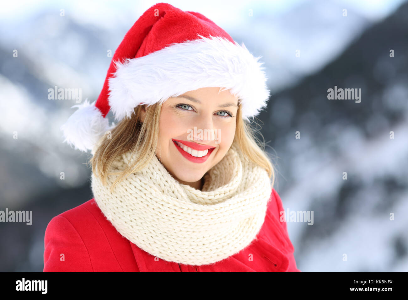 Ritratto di una donna felice in posa con santa claus hat in vacanze di Natale con una montagna innevata in background Foto Stock