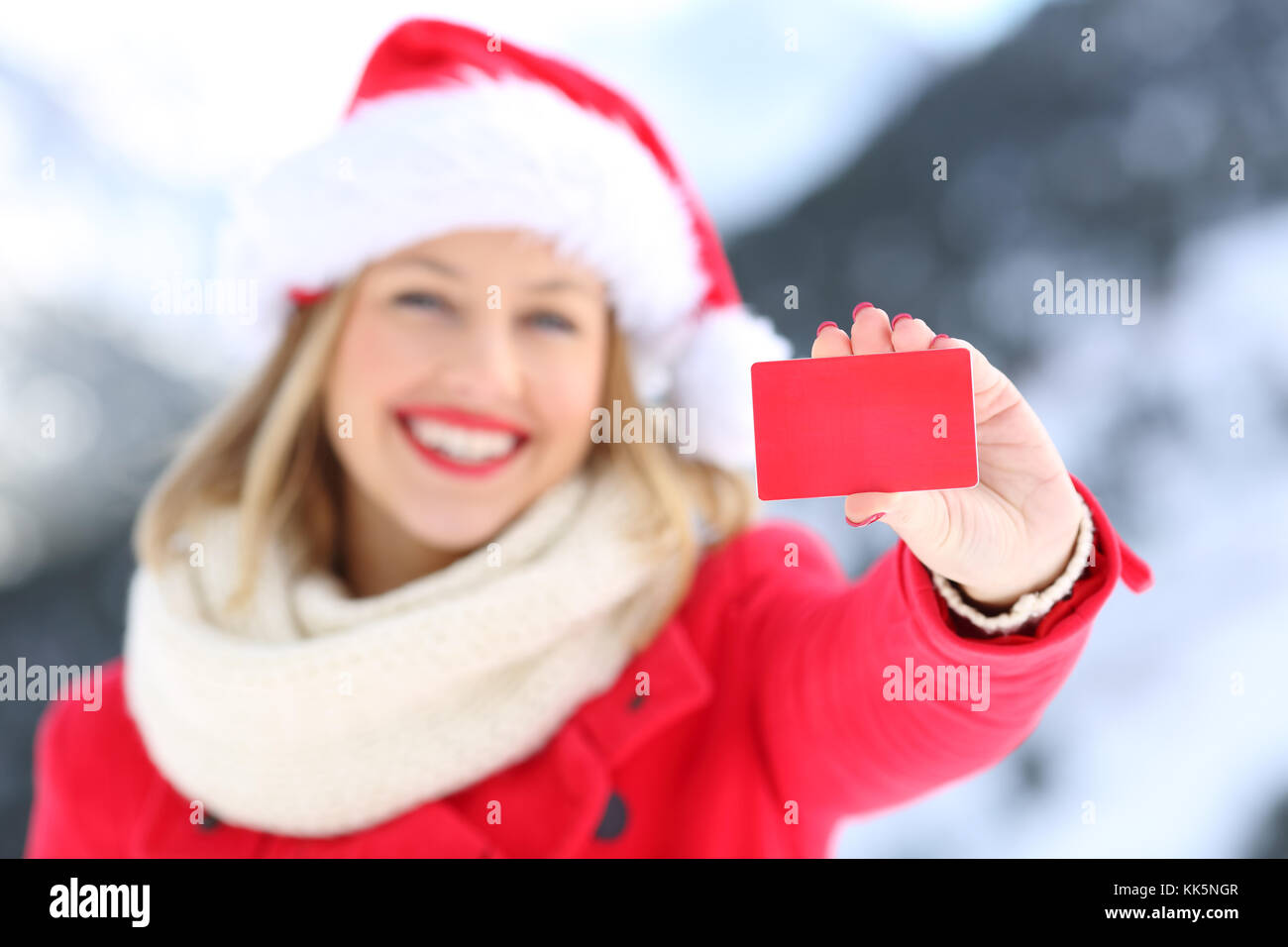 Vista frontale il ritratto di una donna che mostra un fustellato carta di credito in vacanze di Natale con una montagna innevata in background Foto Stock