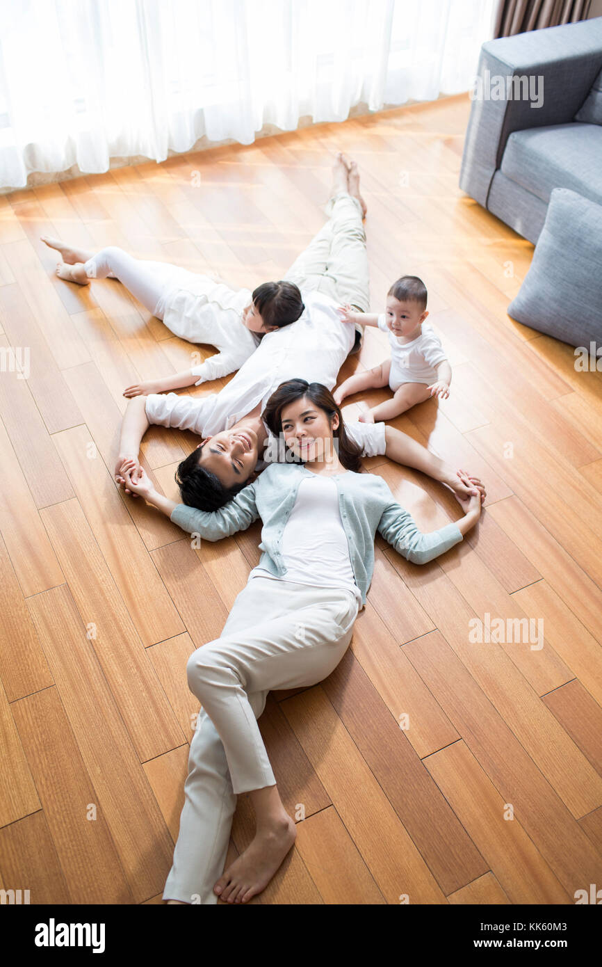 Felice giovane famiglia cinese in appoggio su pavimento in legno Foto Stock