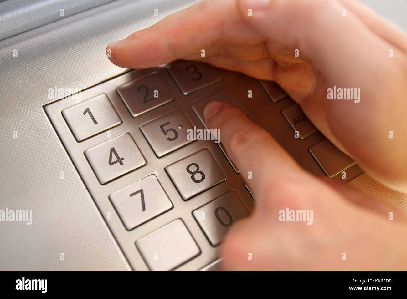 Maschio lato la digitazione del codice di sicurezza egli bianco nasconde con l'altra mano. Foto Stock