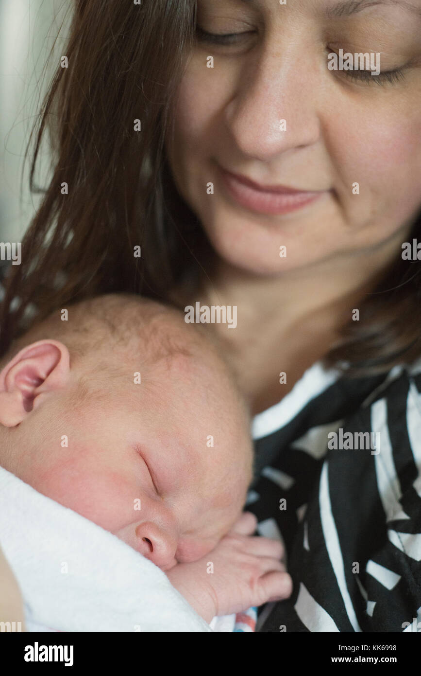 Un neonato essendo trattenuto in ospedale dalla sua madre il giorno in cui è nato. Foto Stock