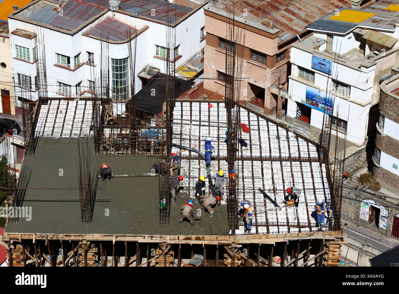 Lavoratori sul sito di costruzione diffusione di calcestruzzo bagnato su piastrelle in polistirene per rendere il piano di un edificio alto, Sopocachi, La Paz, Bolivia Foto Stock