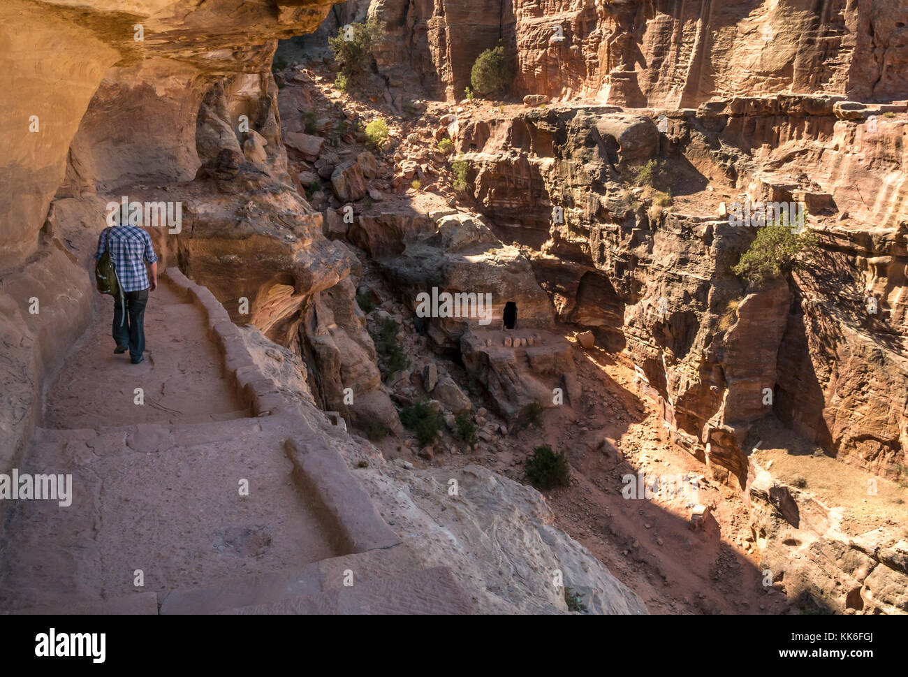 Senior uomo in 60s tourist camminare in arenaria lavorata passaggi sul percorso a piedi di alto luogo del sacrificio, Petra, Giordania, Medio Oriente Foto Stock