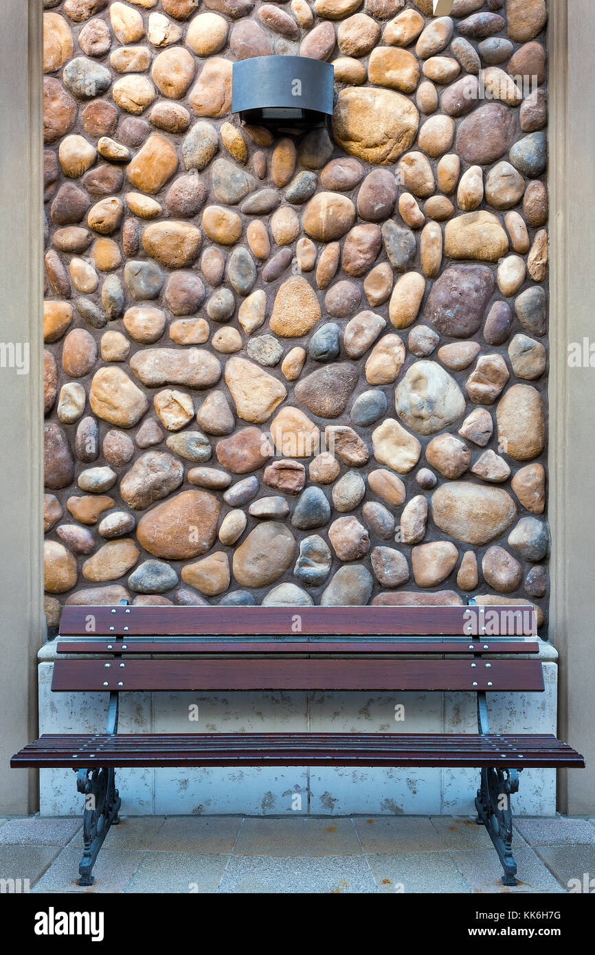 Il giardino esterno panca di legno sul pavimento di pietra di fiume parete di roccia Foto Stock
