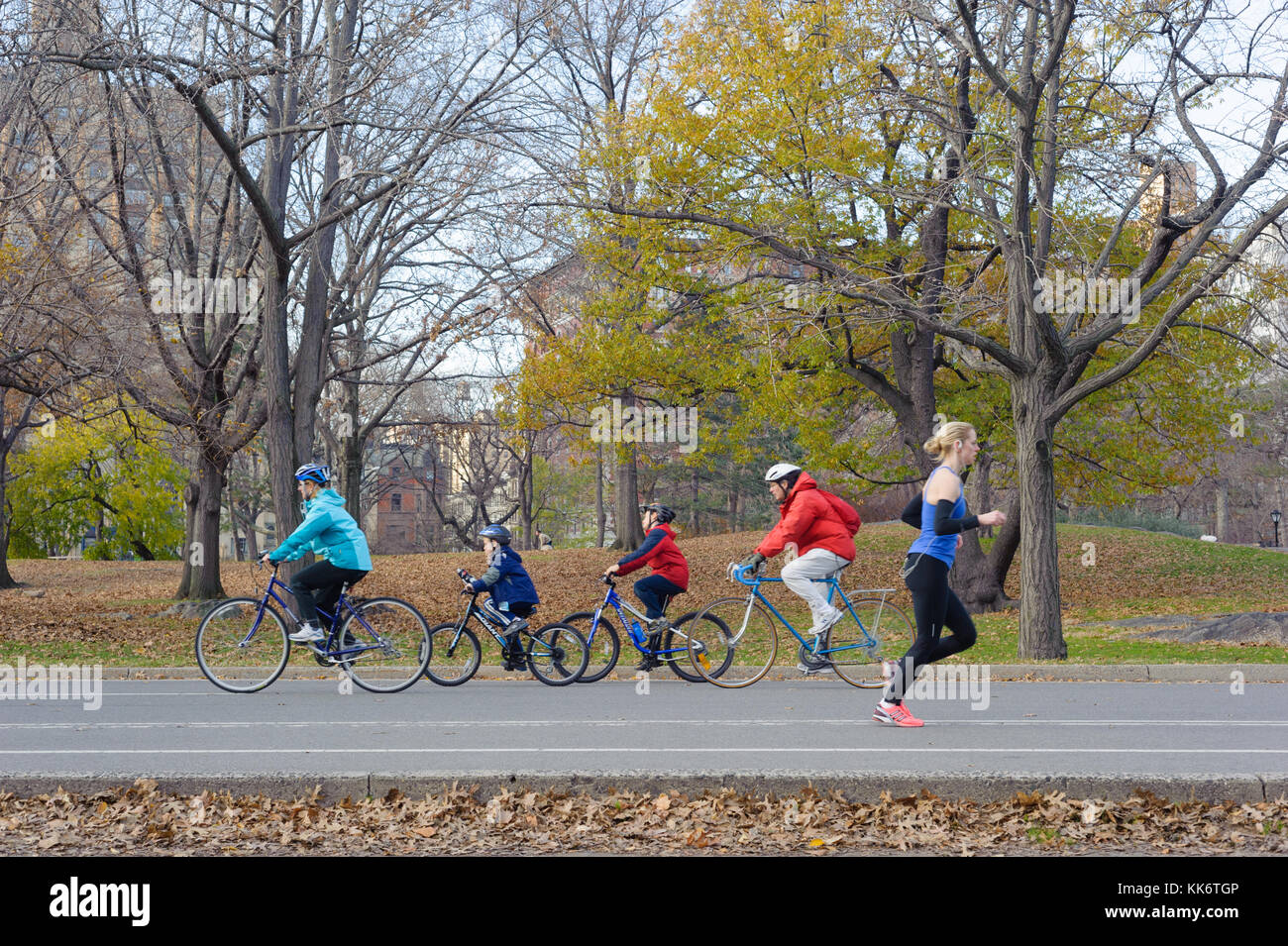 I membri della famiglia e la donna solista ciclismo su central park Foto Stock