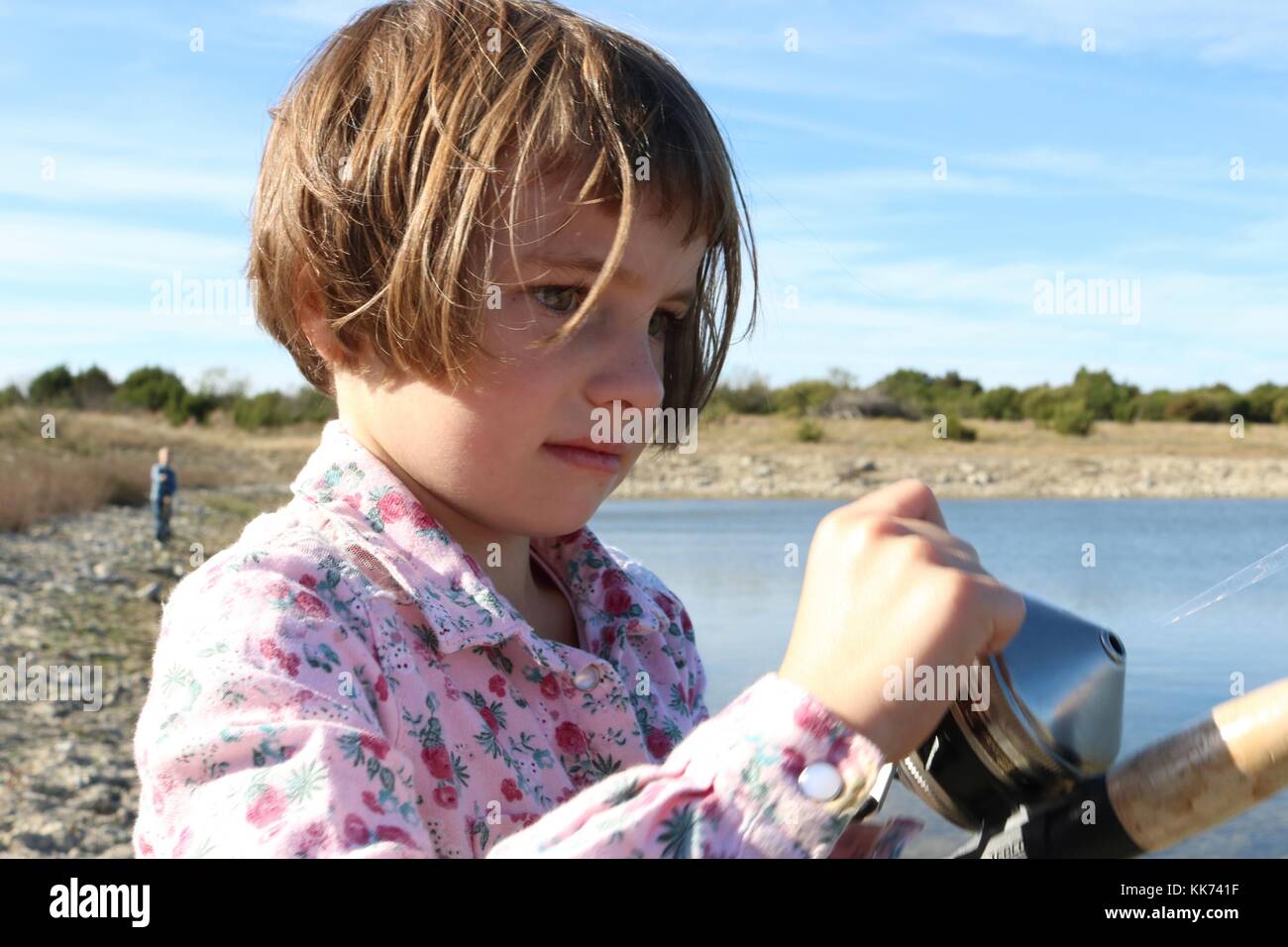 Primo piano della bambina la bobinatura in un pesce ha catturato Foto Stock