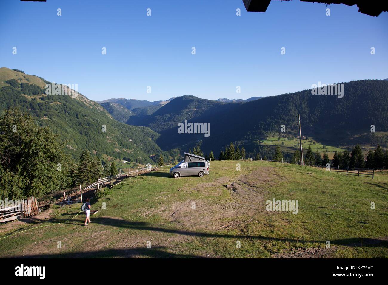 Una femmina di camper di ritornare al suo motorhome in un campo in cima a una collina che domina la valle di Rugova in Kosovo una luminosa giornata di sole. Foto Stock